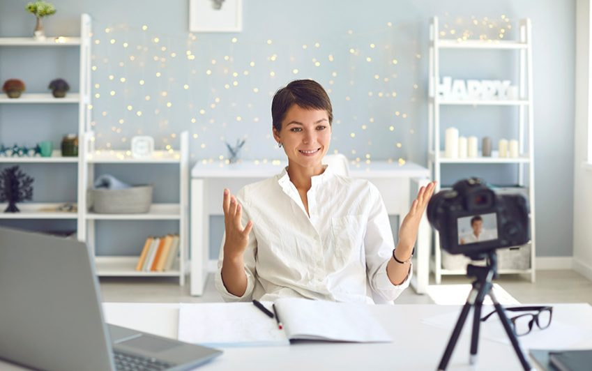 Eine Frau sitzt am Schreibtisch und filmt sich 