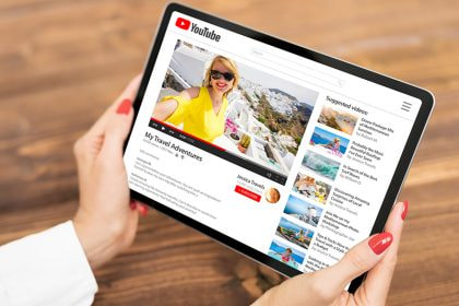 Jemand hält ein Tablet in den Händen, auf diesem ist YouTube zu sehen